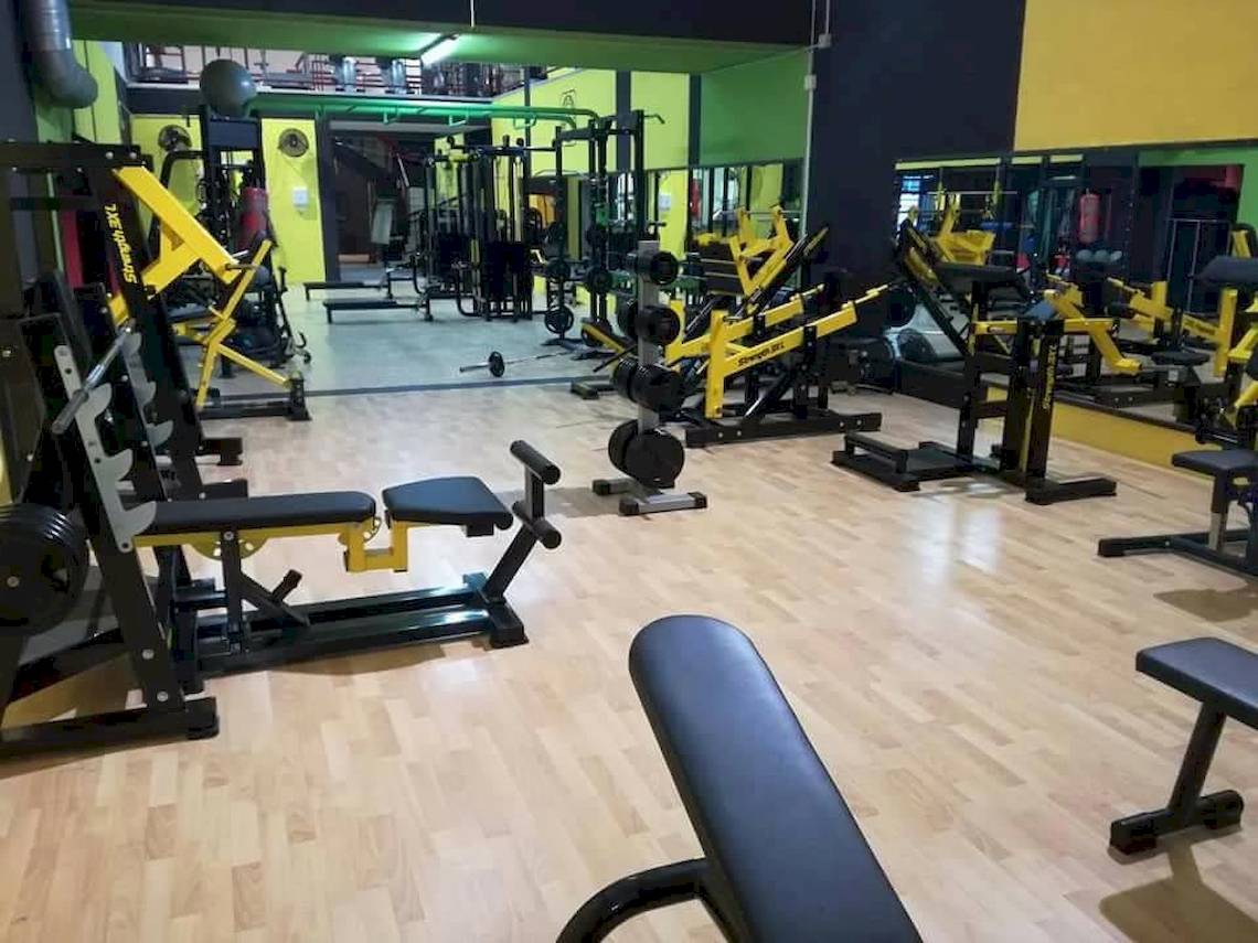Fitnessstudio mit verschiedenen Trainingsgeräten wie Hanteln und Kraftmaschinen.