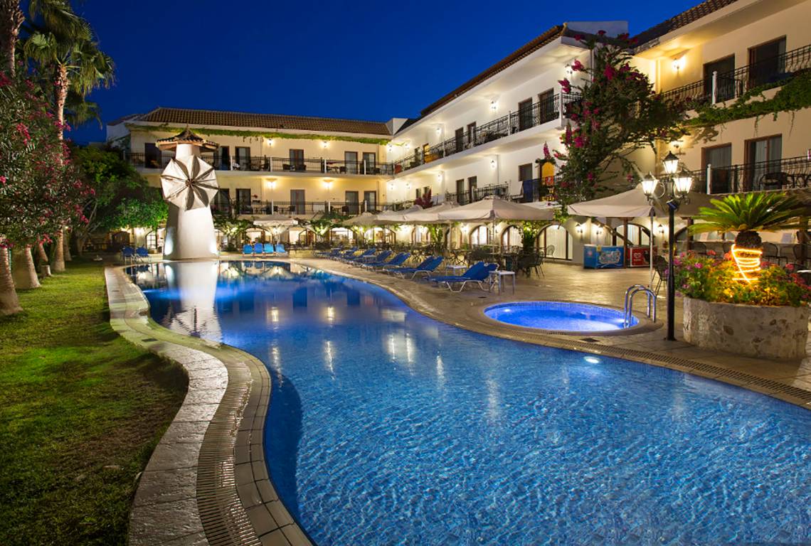 Nachtansicht des Almyrida Beach Hotels mit Swimmingpool und Liegestühlen