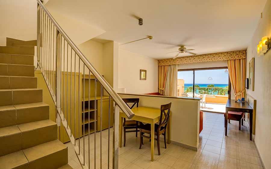 Innenbereich des SBH Taro Beach Hotels mit Tisch, Stühlen und Blick auf das Meer.