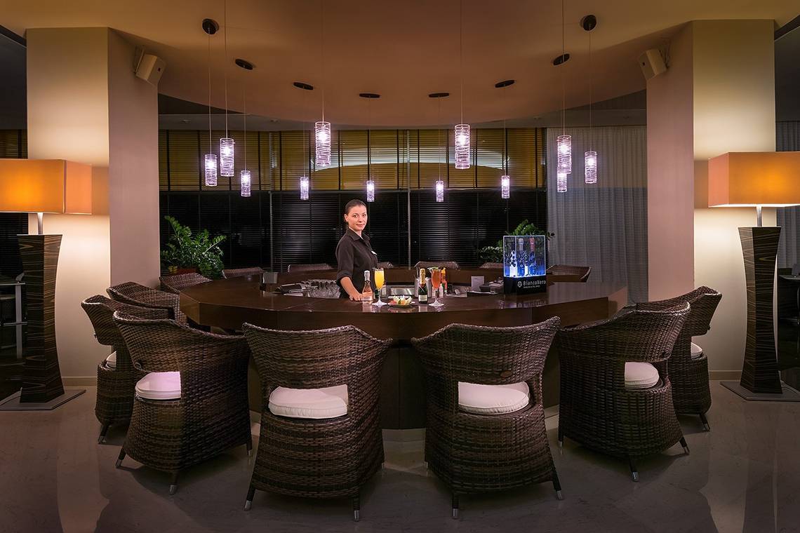 Barbereich des Olympic Palace Resorts mit einer Dame an der Theke und mehreren runden Stühlen um einen Tisch.