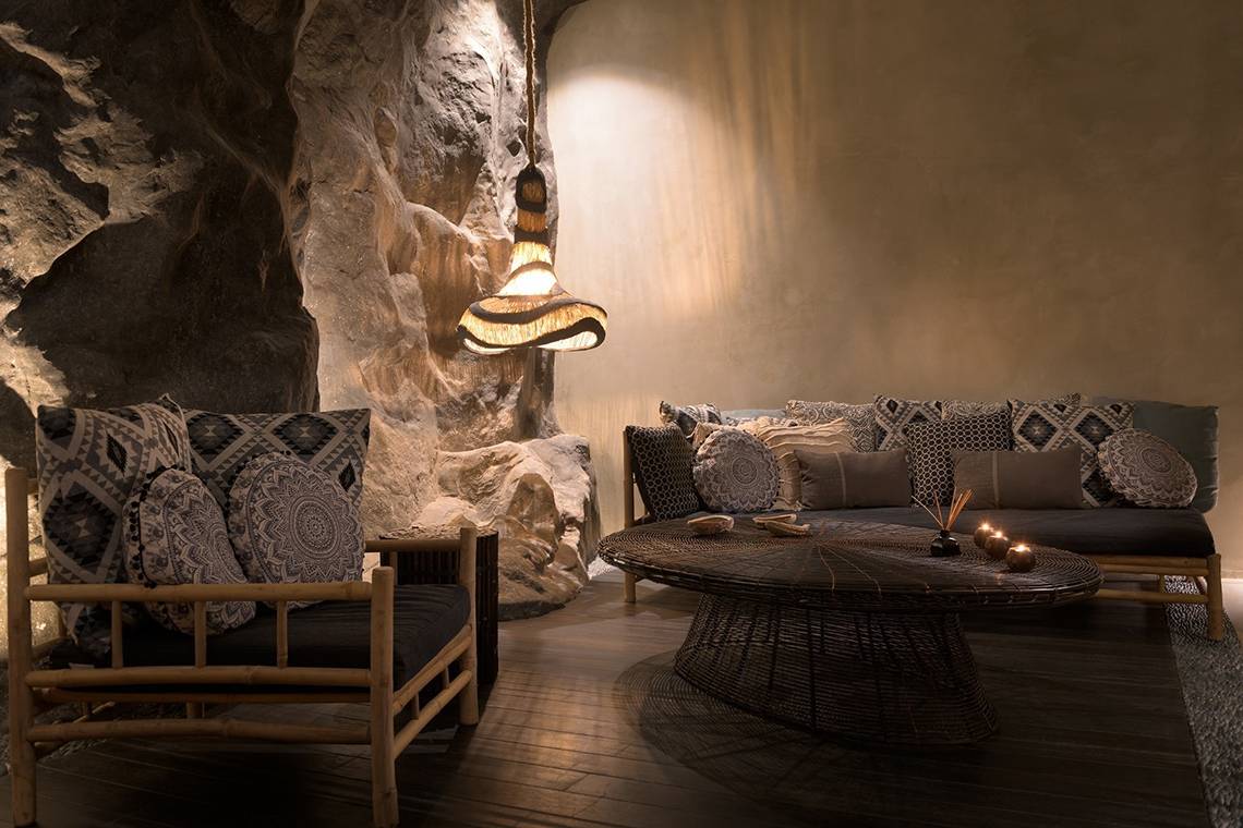 Lounge-Bereich im Olympic Palace Resort mit Steinwand, Sofas, Tischen und Lampen.