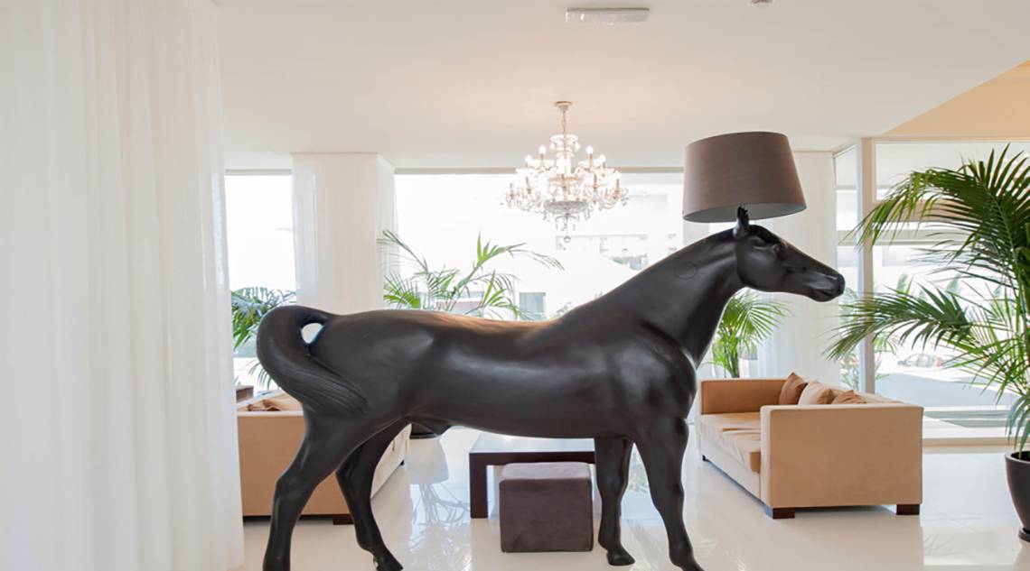 Ein großes schwarzes Pferde-Design, das als Lampenschirm dient, steht in einer eleganten Hotellobby.