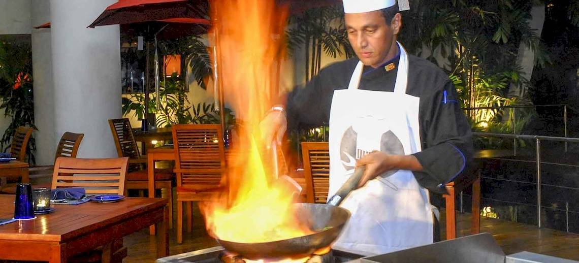 Koch vom Occidental Eden Beruwala brät mit einem brennenden Wok in der Hotelküche