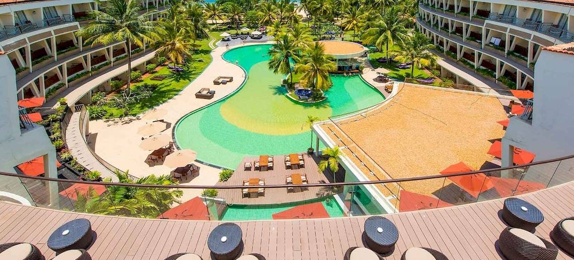 Aussicht auf das Occidental Eden Beruwala Resort mit Swimmingpool, Sonnenliegen und Gebäuden.