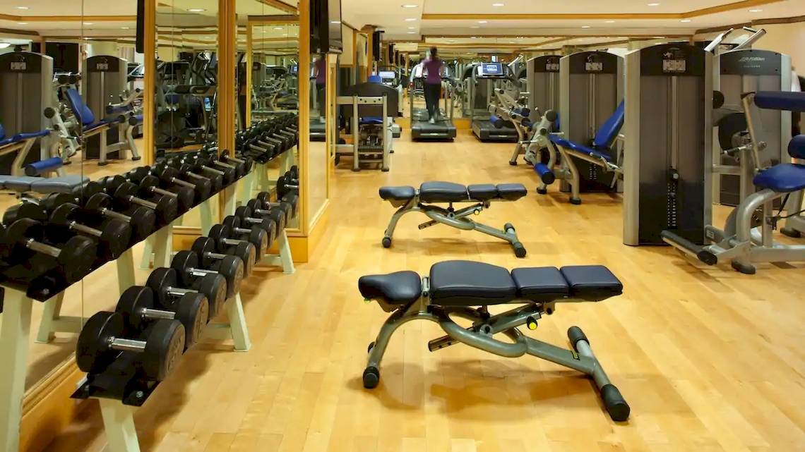 Fitnessstudio im Grand Hyatt Muscat mit verschiedenen Trainingsgeräten und einer Person, die ein Laufband benutzt.
