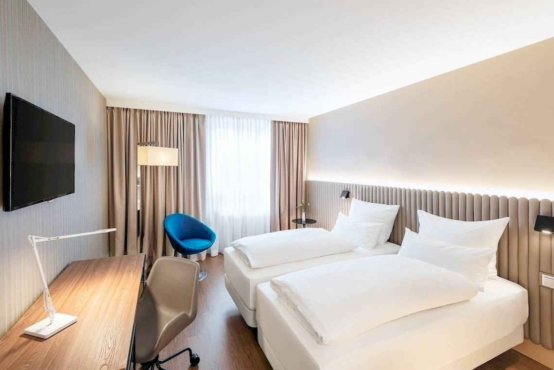 Zimmer im NH Hamburg Altona Hotel mit zwei Betten, Schreibtisch und Fernseher.