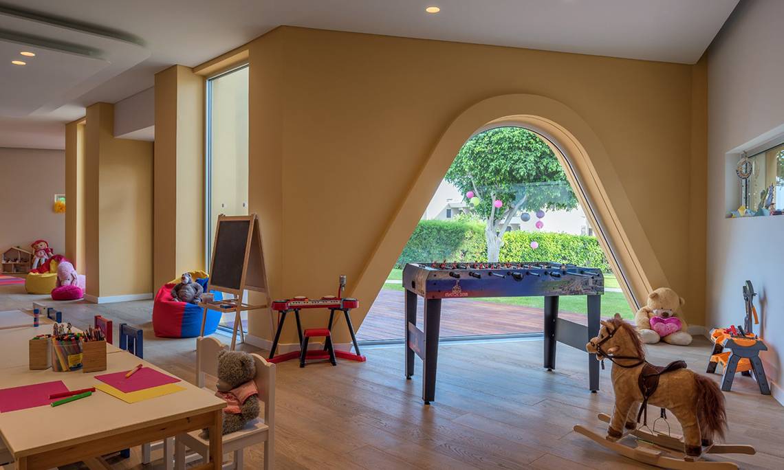Kinderzimmer im Mediterranean Beach Hotel mit Tisch, Stühlen und Spielzeug.