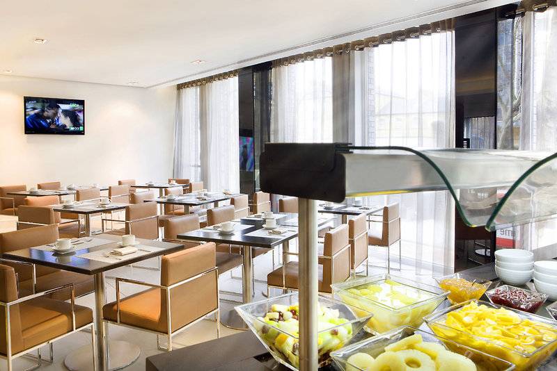 Frühstücksraum im H10 London Waterloo Hotel mit Fernseher und verschiedenen Speisen.