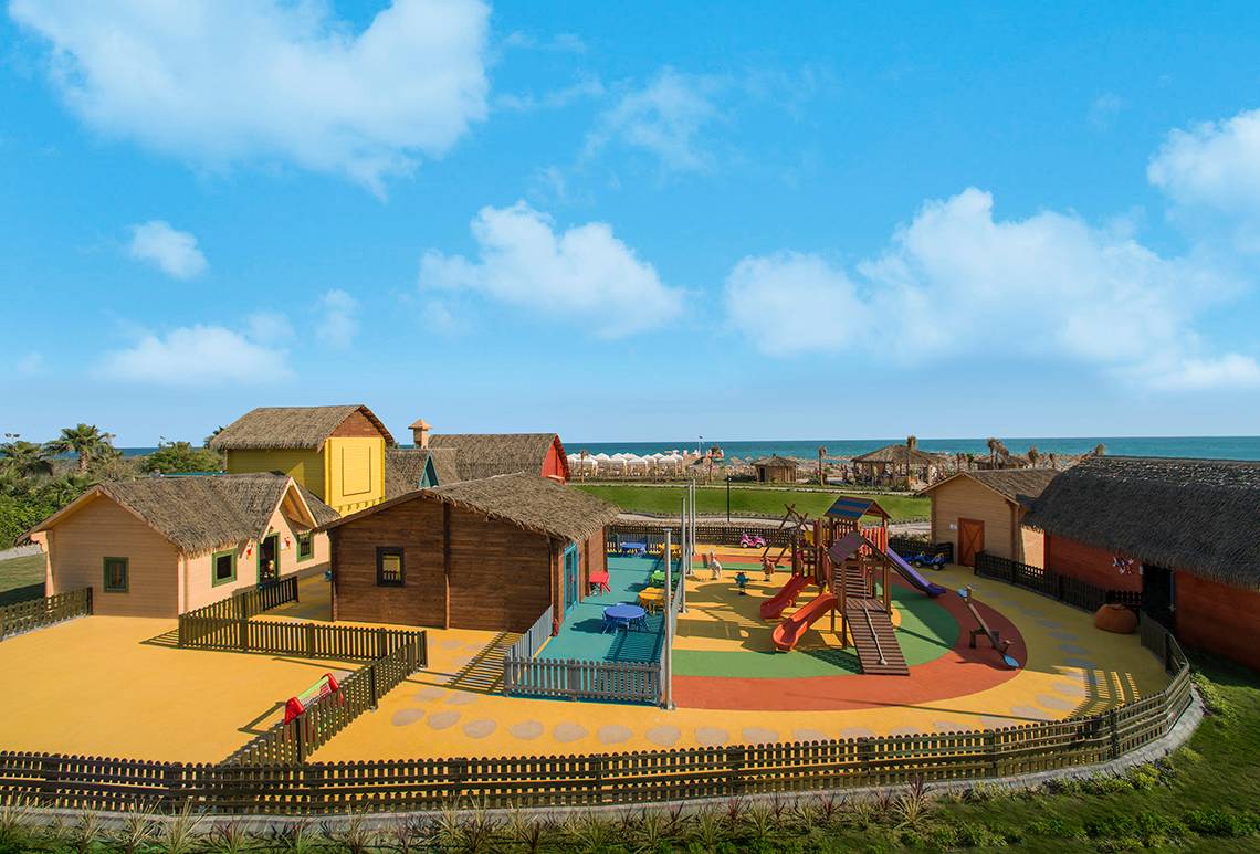Außenansicht des Kinderspielplatzes im Aska Lara Resort & Spa mit bunten Spielgeräten und Hütten.