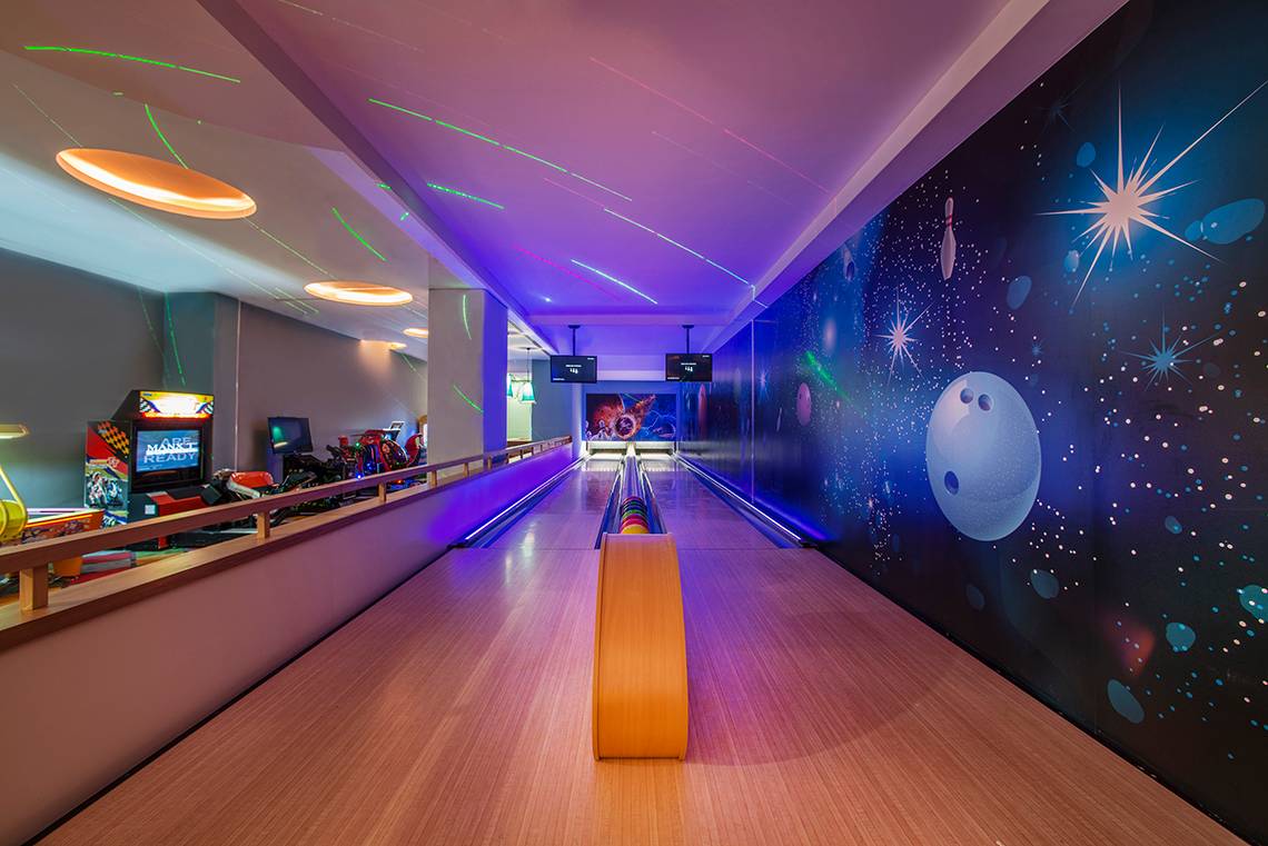 Innenansicht der Bowlingbahn im Aska Lara Resort & Spa mit bunten Neonlichtern und einer großen Wandmalerei.