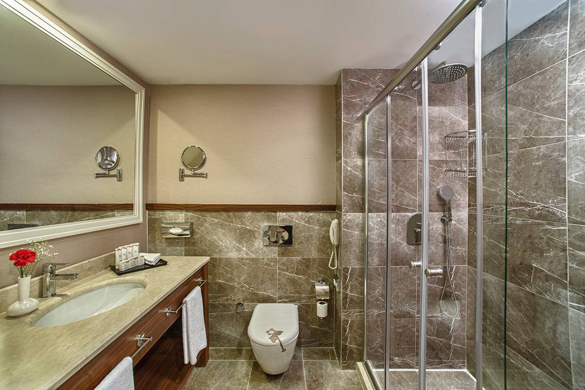 Badezimmer des Aska Lara Resort & Spa mit Waschbecken, Spiegel, Toilette und Duschkabine.