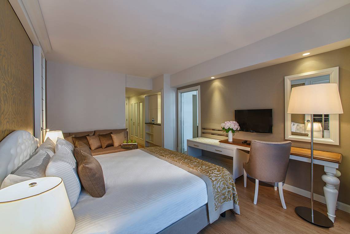 Hotelzimmer im Aska Lara Resort & Spa mit einem großen Bett, Sofa, Schreibtisch und Fernseher.