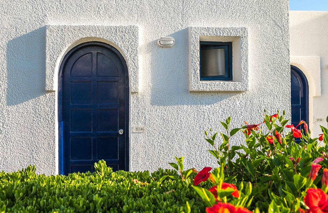Eingang des Aeolos Beach Hotel - Kos mit blauer Tür und rotem Blumenbusch davor