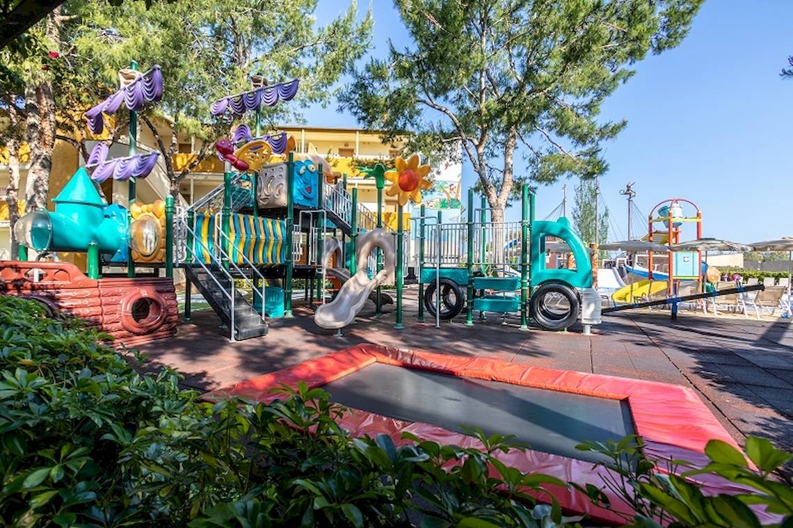 Spielplatz im Freien im Zafiro Tropic Hotel mit bunten Spielgeräten und einem Trampolin.