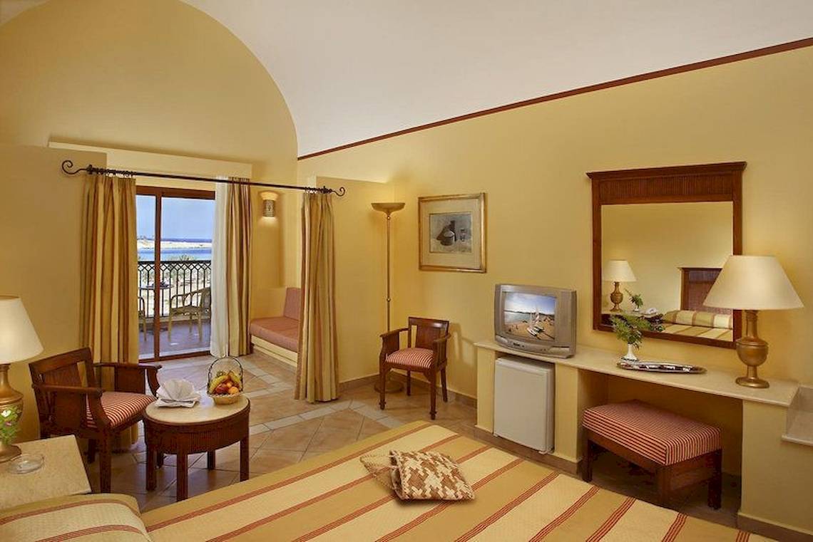 Innenansicht eines Hotelzimmers im Jaz Solaya mit Bett, Tisch, Stühlen, Fernseher und Balkonsicht.