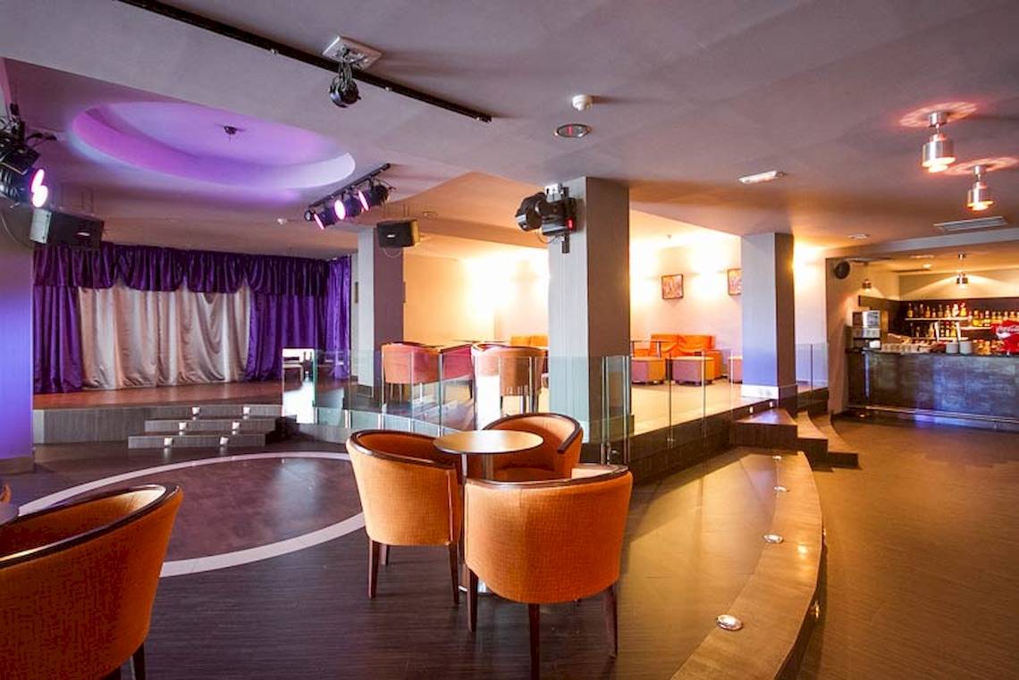 Innenbereich des Lanzarote Village Hotels mit orangefarbenen Stühlen und einer Bühne.