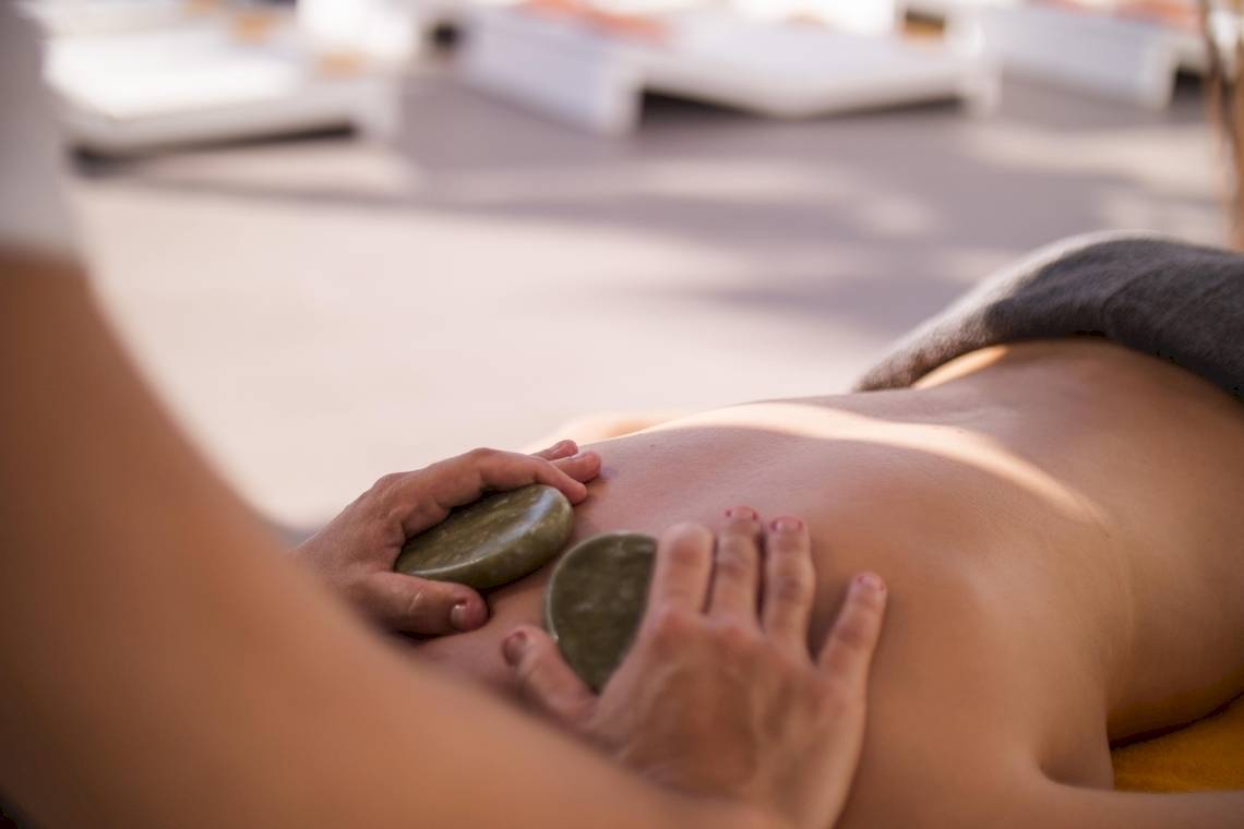 Eine Person, die eine Massage im Ibiza Sun Apartments Hotel genießt, mit Steinen auf dem Rücken.