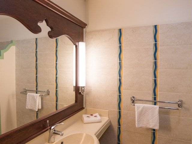 Badezimmer im Pierre & Vacances Village Sainte Luce mit Spiegel, Waschbecken, Handtüchern und Wandmustern.