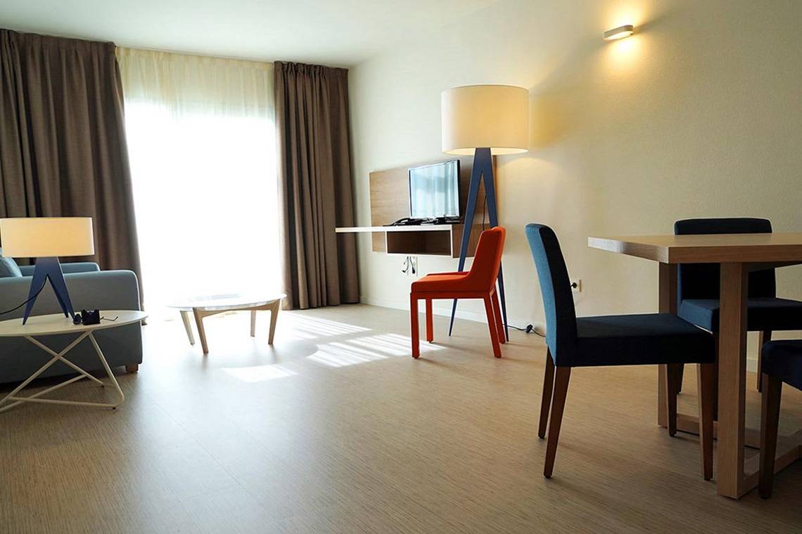 Hotelzimmer mit Schreibtisch, Sofa, Tisch und Stühlen.