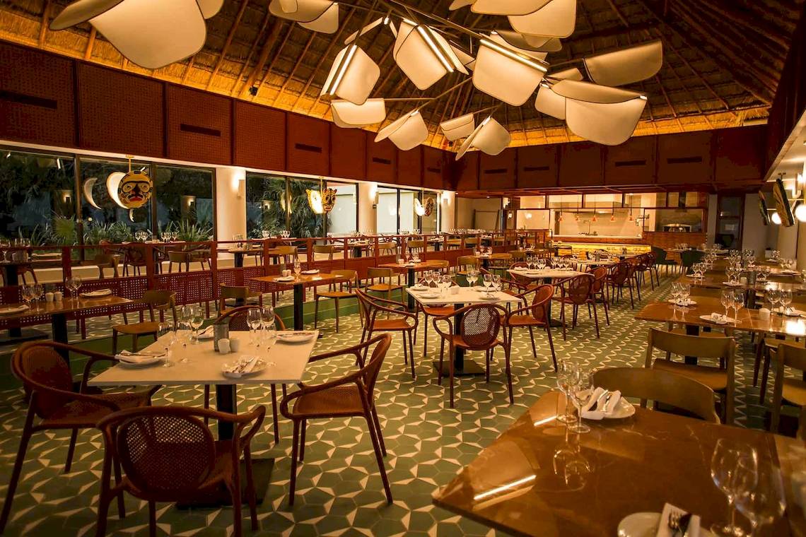 Innenansicht des Restaurants im Bahia Principe Luxury Akumal Hotel mit gedeckten Tischen und Stühlen.