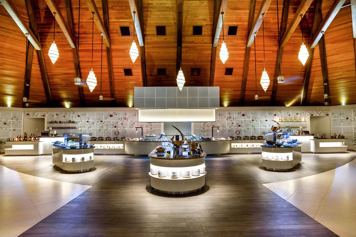 Innenansicht des Restaurants im Kurumba Maldives mit Holzdecke und Buffets.