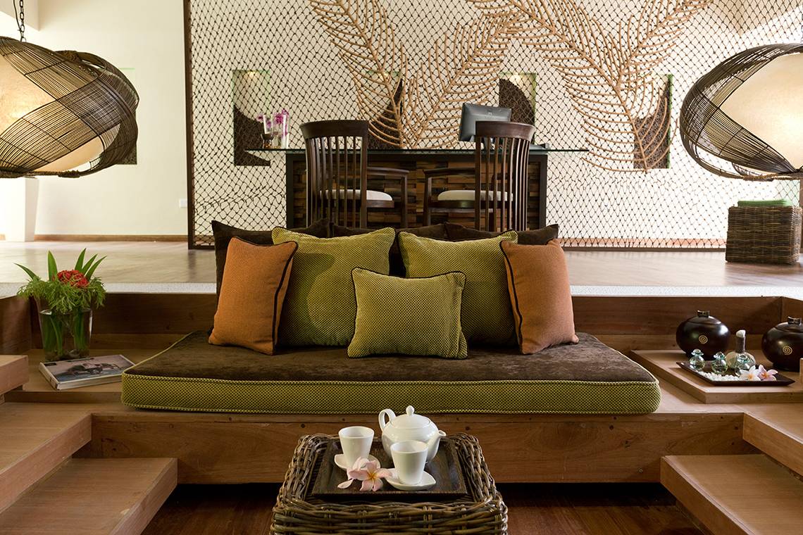 Hotel-Lounge-Bereich mit einem Sofa, grünen Kissen, einem Tisch und einer Tasse Tee auf dem Tisch.