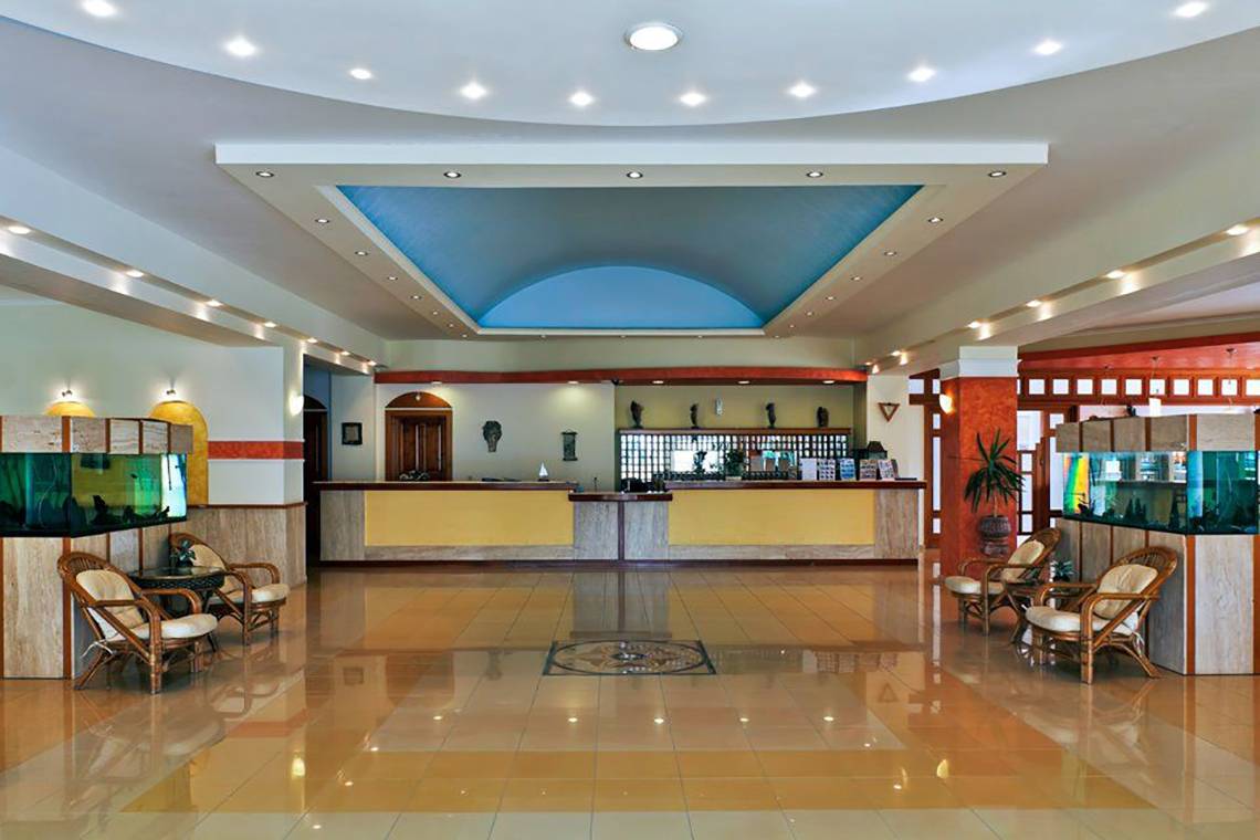 Empfangsbereich des Gaia Village Hotels mit hoher Decke und blauer Akzentbeleuchtung.