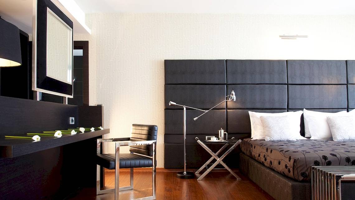Schlafzimmer im Sentido Port Royal Villas & Spa Hotel mit schwarzem Kopfteil, Schreibtisch und Nachttisch.