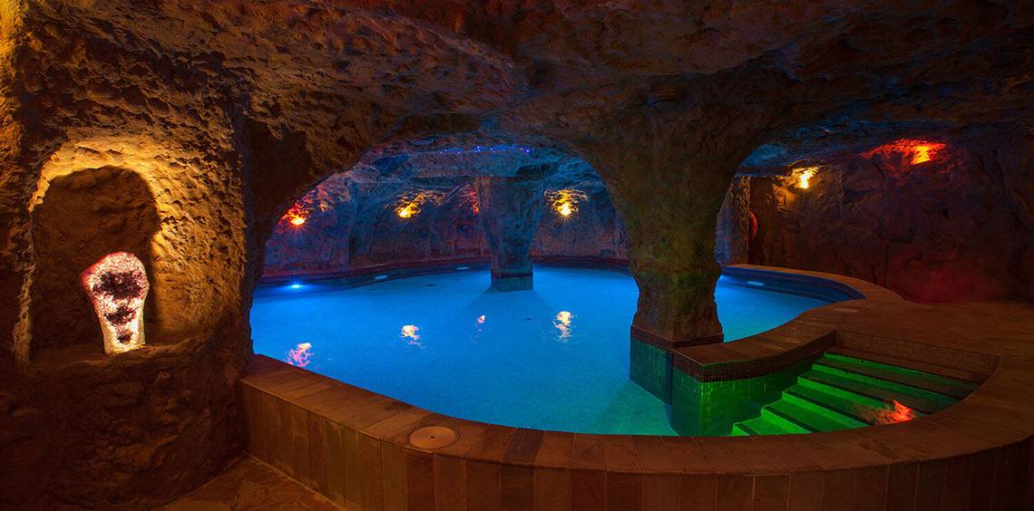 Unterirdischer Pool im Lopesan Costa Meloneras Resort & Spa mit farbigen Lichtern und Steinwand.