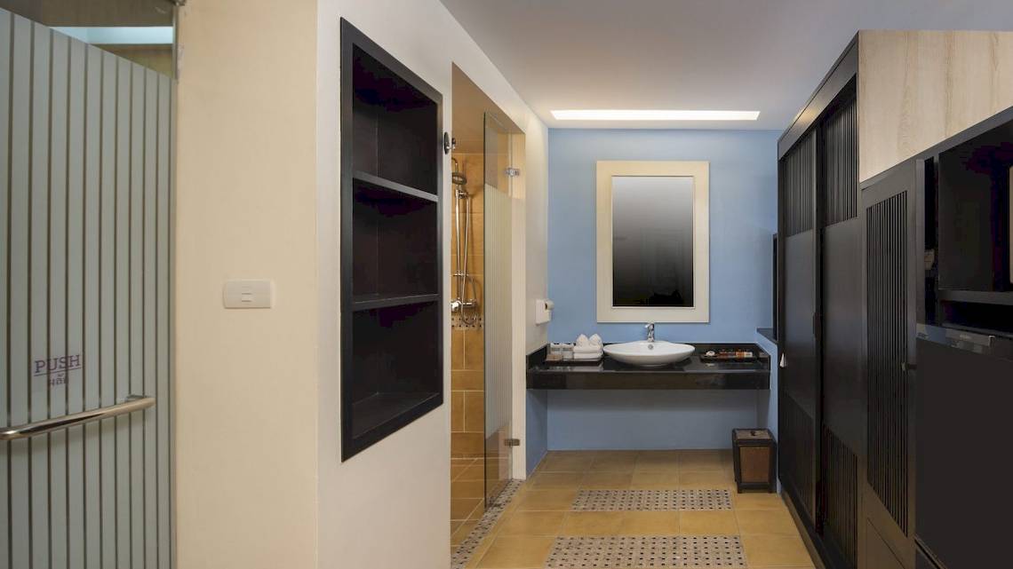 Badezimmer des Anyavee Tubkaek Beach Resort mit blauen Wänden, einem Waschbecken, Spiegel und offenen Schrank.