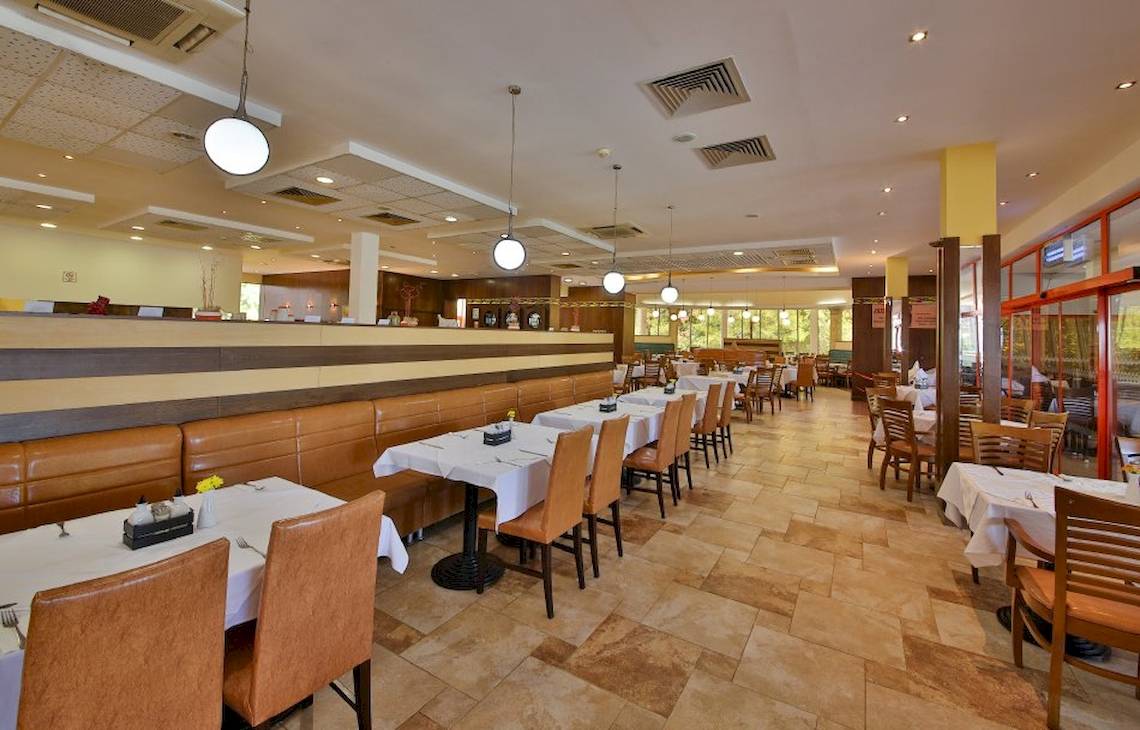Innenansicht des Restaurants im Kaliakra Beach Hotel mit gepolsterten Bänken und Tischen.