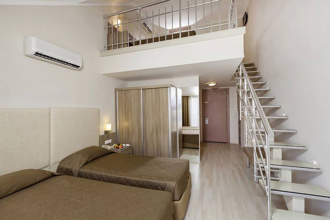 Doppelzimmer mit Balkon im Calimera Hane Garden Hotel, mit zwei Betten, Klimaanlage, und einer Treppe zur oberen Etage.
