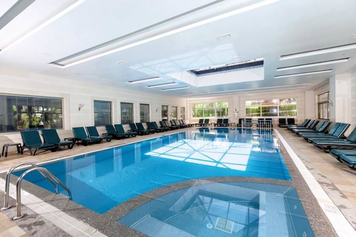 Innenpool des Calimera Hane Garden Hotels mit Liegestühlen und blauem Wasser