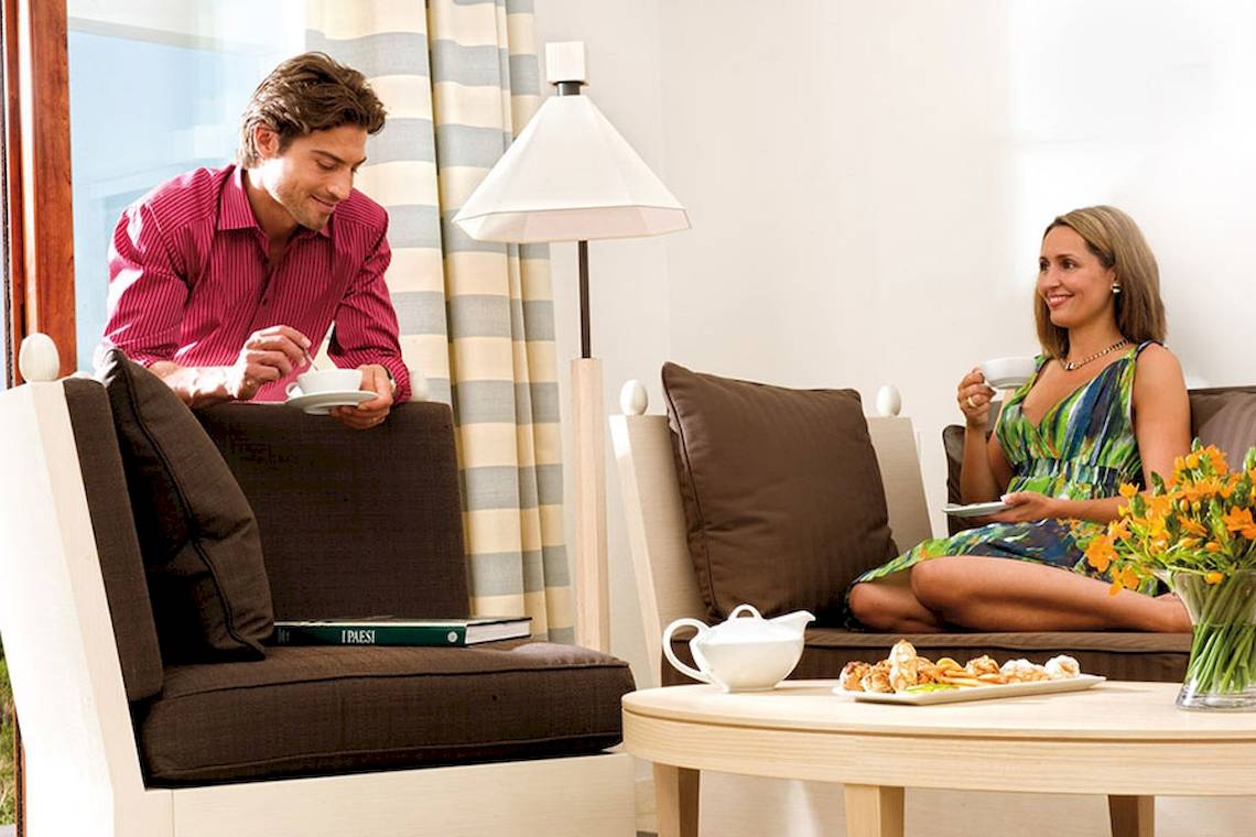 Mann und Frau in einem Hotelzimmer mit Kaffee und Gebäcken.