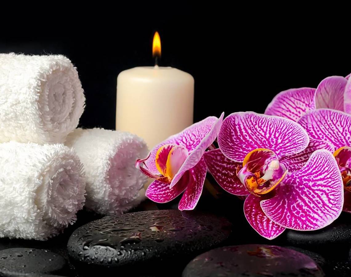 Spa-Einrichtung mit Kerze, Orchideen, Handtüchern und Steinen im Millennium Plaza Downtown Hotel