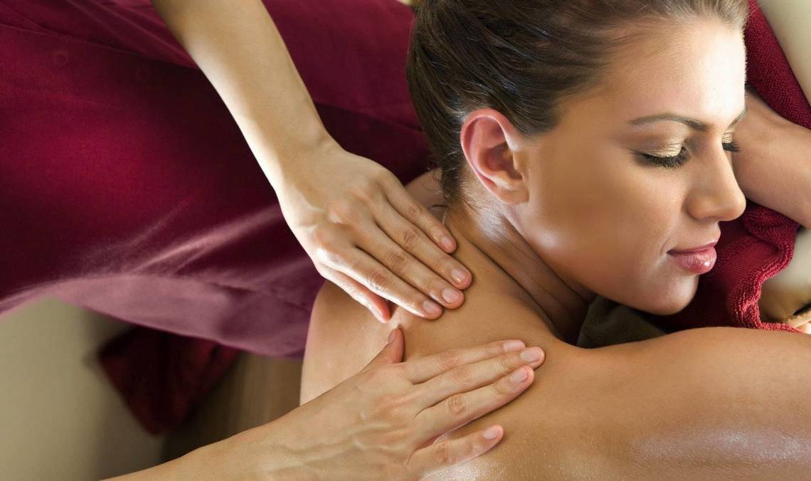 Frau erhält Schultermassage im Hotel, während sie entspannt auf dem Rücken liegt.