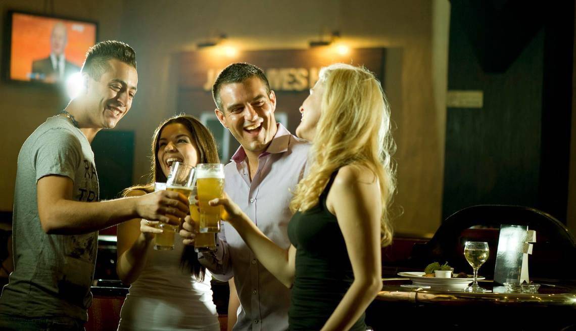 Gruppe lachelnder Leute, die Bier in einer Bar trinken.