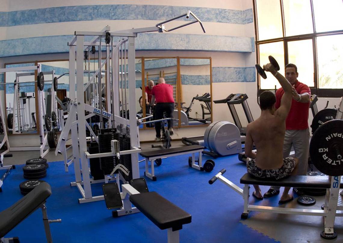 Fitnessraum im Melia Varadero Hotel mit Geräten und einem Mann, der Gewichte hebt.