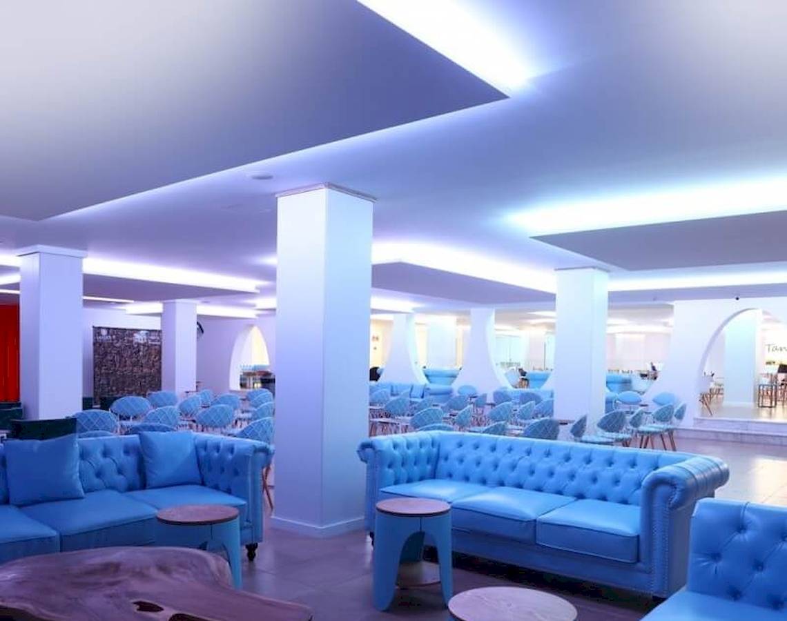 Innenbereich des Sandos El Greco Beach Hotels mit blauen Sofas und Tischen