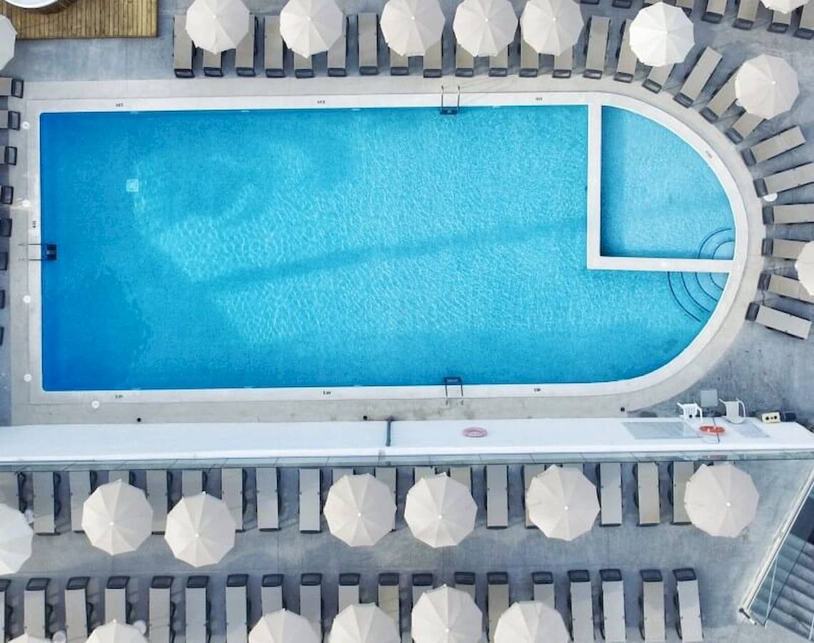 Luftaufnahme des Sandos El Greco Beach Pools mit Sonnenliegen und Sonnenschirmen