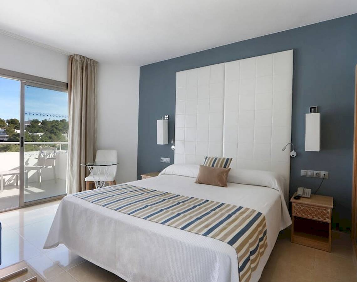 Schlafzimmer im Sandos El Greco Beach Hotel mit Bett, Balkon und modernen Möbeln.