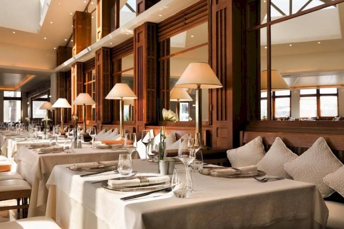 Innenbereich des Porto Sani Hotels mit gedeckten Esstischen und Lampen.