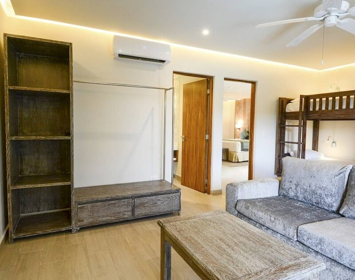Wohnzimmer im Sandos Caracol Eco Resort mit Sofa, Couchtisch, Bücherregal und Klimaanlage.