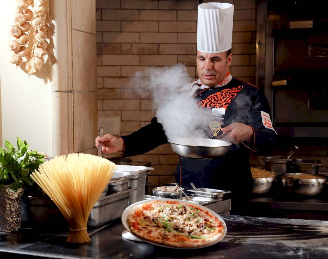 Koch im LABRANDA Royal Makadi Hotel, der eine Pizza zubereitet und Nudeln kocht.