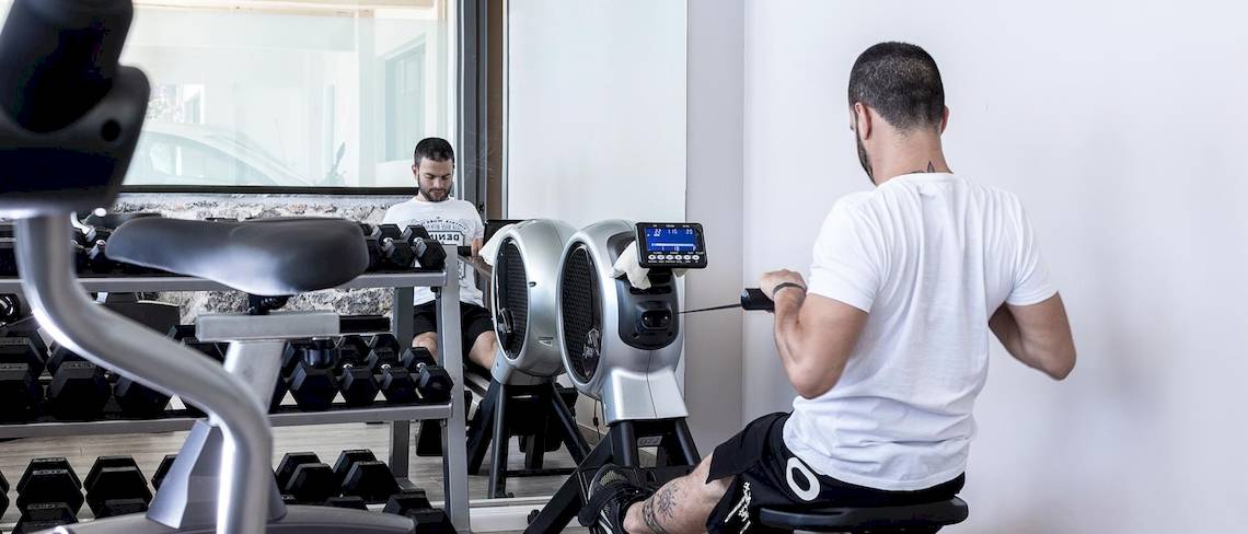 Zwei Männer im Aeolos Beach Resort auf Korfu nutzen Fitnessgeräte im Fitnessstudio.