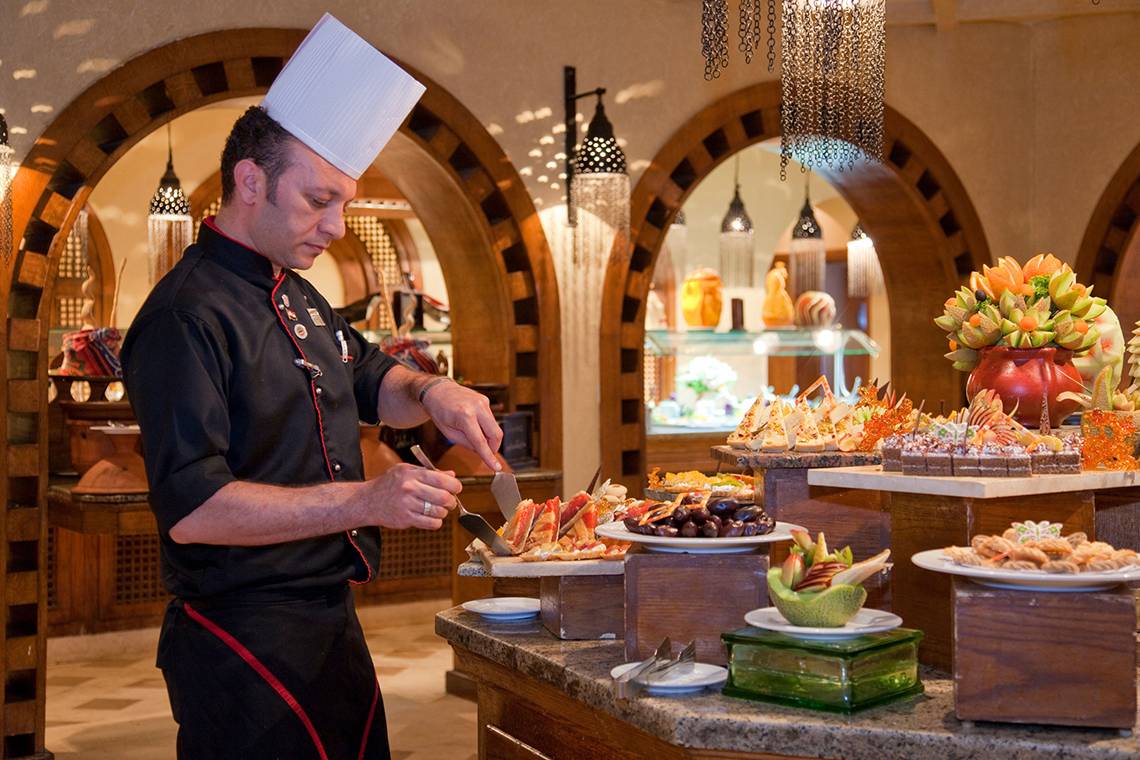 Koch des Ghazala Gardens Hotels bereitet Gerichte am Buffet zu
