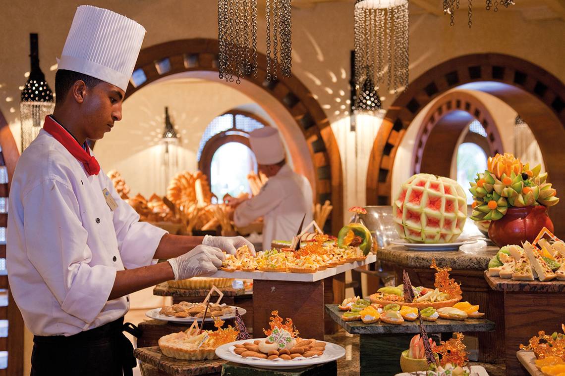 Ein Koch im Ghazala Gardens Hotel serviert eine Auswahl an Gerichten auf dem Buffettisch.