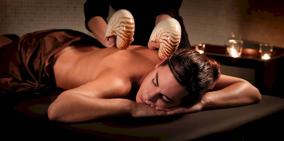 Frau erhält Massage im H10 Estepona Palace mit Muschelwerkzeugen.