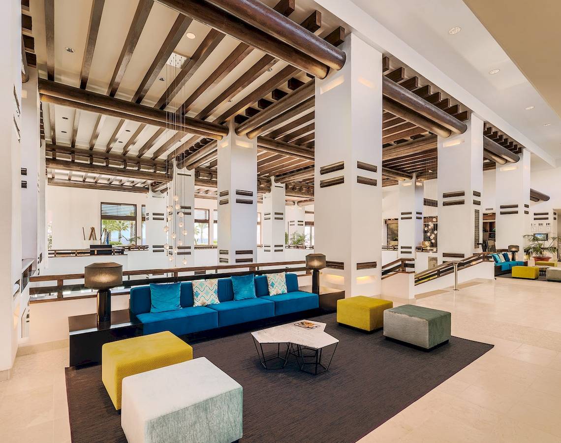 Innenansicht des H10 Estepona Palace Lobbys mit blauem Sofa und gelben Hockern.