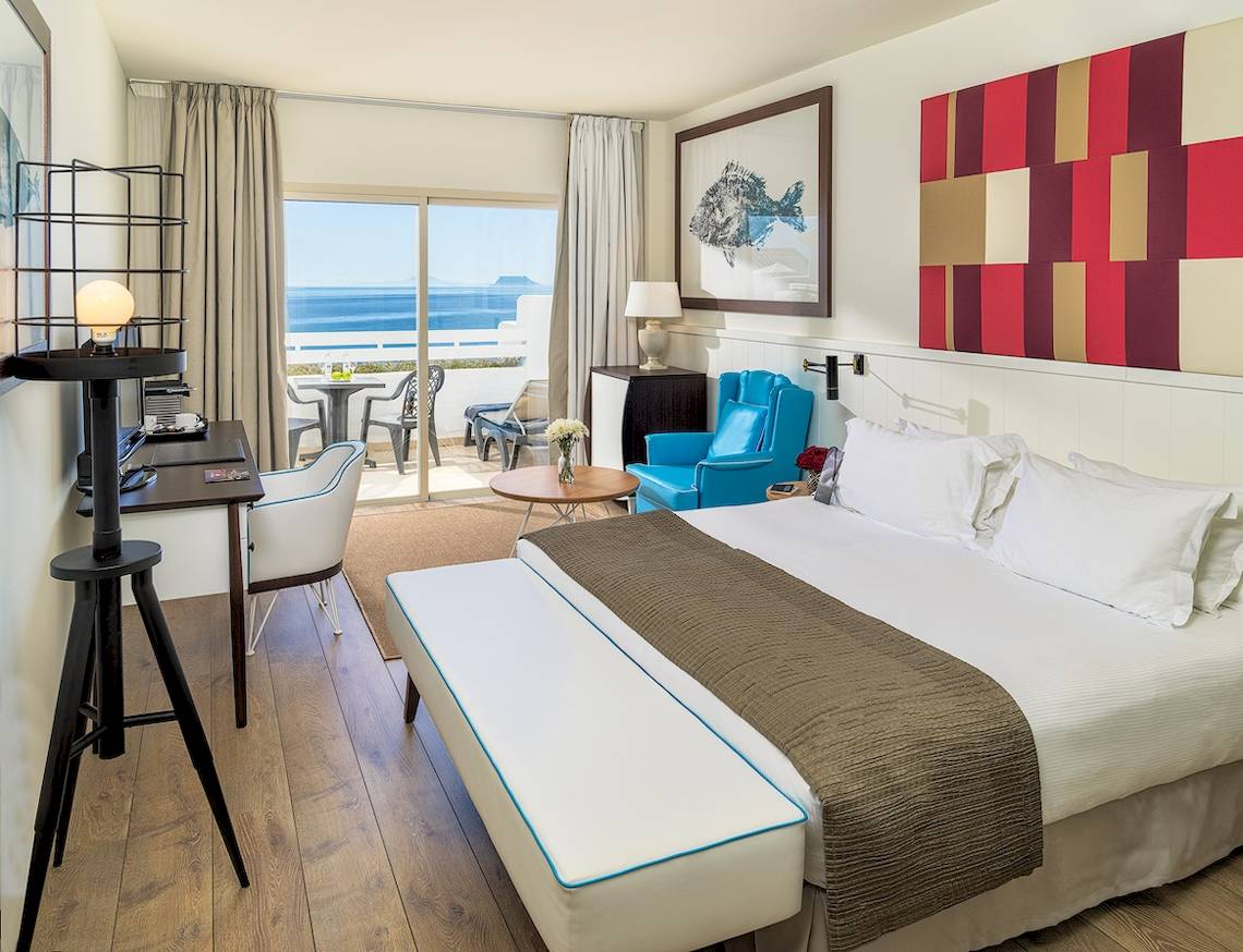 Innenansicht eines Hotelzimmers im H10 Estepona Palace mit Blick auf das Meer und eine Terrasse.